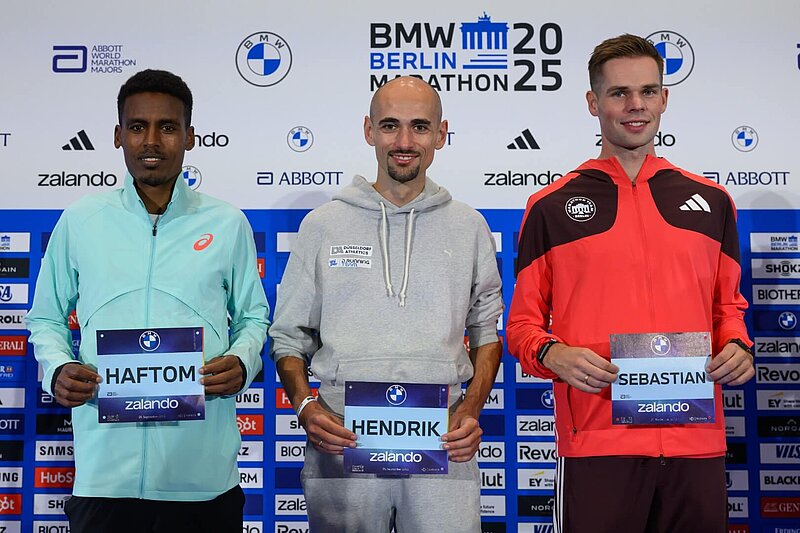 From left to right: Haftom Welday, Hendrik Pfeiffer, and Sebastian Hendel hold up their race numbers for the camera.