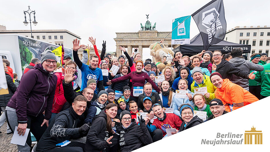 [Translate to English:] Eine Gruppe jubelnder Läufer:innen beim Neujahrslauf vor dem Brandenburger Tor. Eine ausgelassen jubelnde Gruppe von Neujahrslauf-Teilnehmer:innen feiert vor dem Brandenburger Tor den Einstieg ins neue Laufjahr. ©Camera4_Eberhard Thonfeld / SCC EVENTS