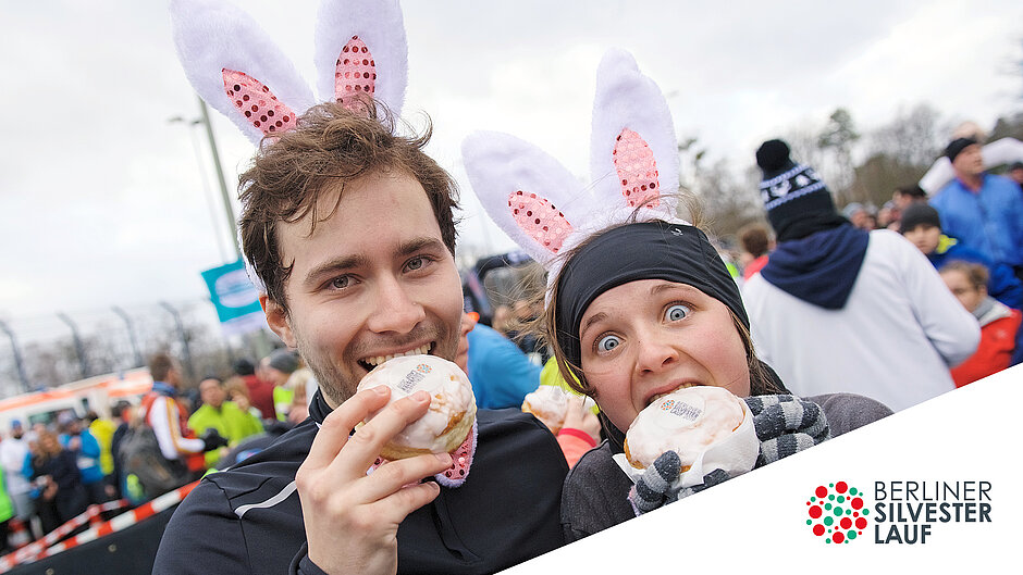 Ein Pärchen genießt die Berliner Pfannkuchen im Ziel.  Kostümiertes Pärchen mit Berliner Pfannkuchen, der leckeren Belohnung im Ziel. ©Tilo Wiedensohler / SCC EVENTS