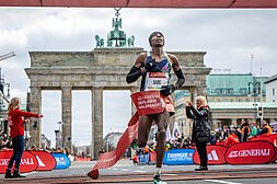 Sebastian Sawe crosses the finish line of the GENERALI BERLIN HALF MARATHON, with the Brandenburg Gate in the background