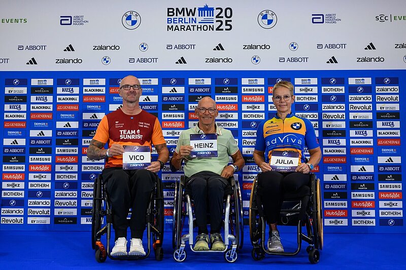 From left to right: Vico Merklein, Heinz Frei, and Julia Dierkesmann hold up their race numbers for the camera.