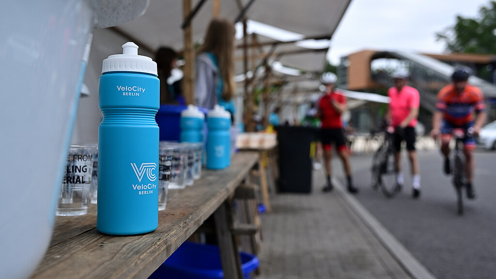 Die offizielle Event Flasche steht auf einem Tisch mit Bechern voll Wasser © SCC EVENTS / Petko Beier