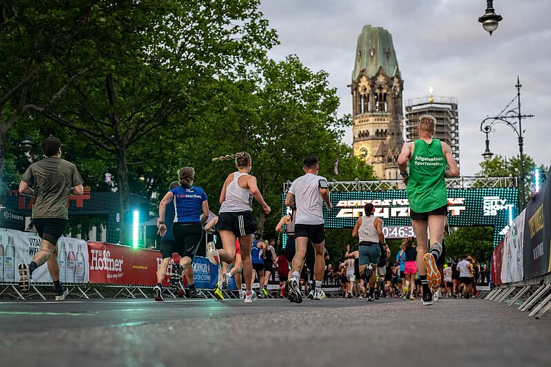 Runners just before the finish line of the adidas Runners City Night 2025, with the Kaiser Wilhelm Memorial Church in the background.