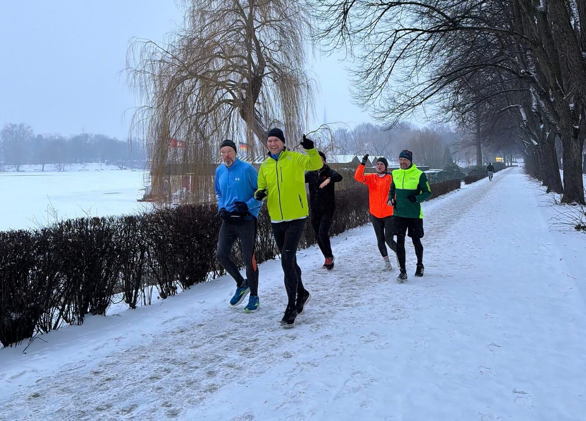 Fünf der Teilnehmer:innen joggen locker entlang einer schneebedeckten Allee.