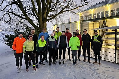 Teilnehmende des SPOBIS Run & Talk by SCC EVENTS stehen im Schnee. Im Hintergrund die Alster.