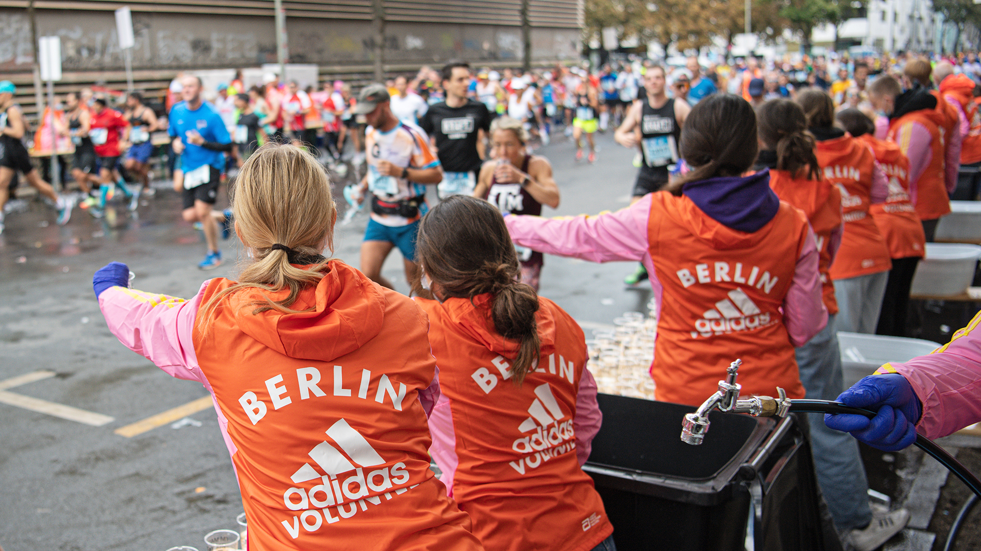 [Translate to English:] Volunteers bei der Wasserausgabe.  Volunteers reichen den Teilnehmer:innen des BMW BERLIN-MARATHON Wasser. ©Annegret Hilse / SCC EVENTS