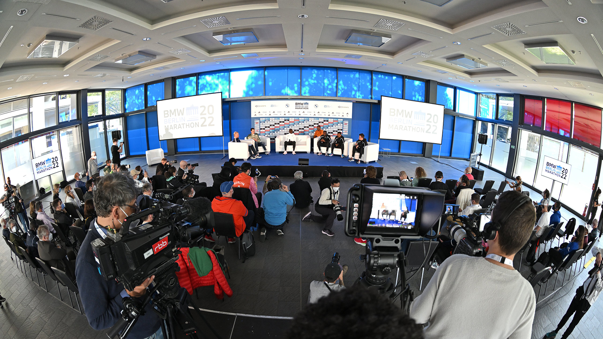 [Translate to English:] Bühne mit Interviewgästen bei Pressekonferenz. Bühne, Zuschauer und Medien bei der Pressekonferenz der Top-Athleten des BMW BERLIN-MARATHON. ©Petko Beier / SCC EVENTS