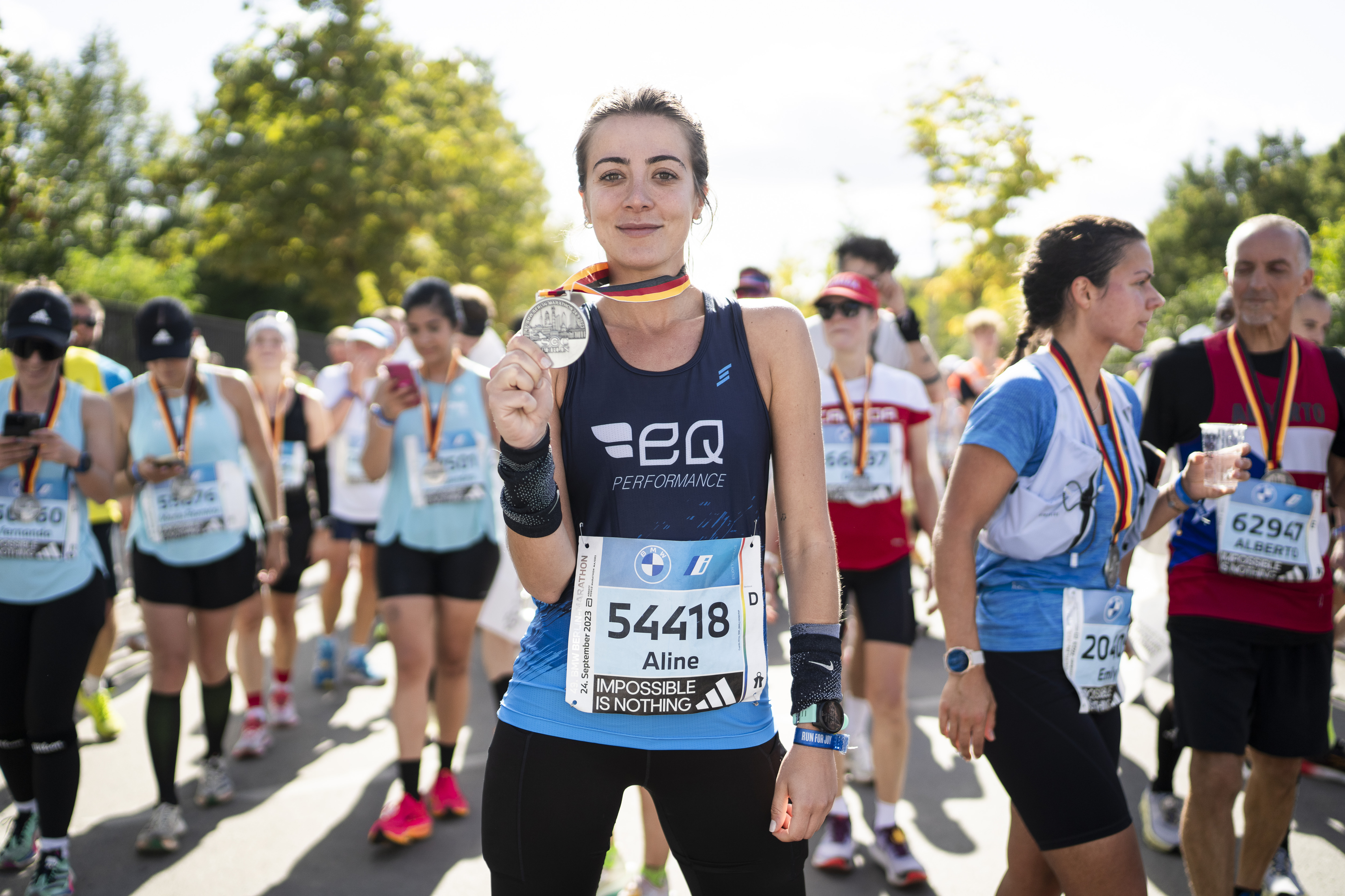 BMW BERLIN-MARATHON 2023: female runner holds her medal up to the camera © SCC  EVENTS / Sebastian Wells